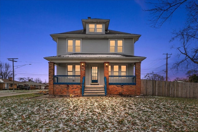 american foursquare style home with fence, covered porch, and brick siding