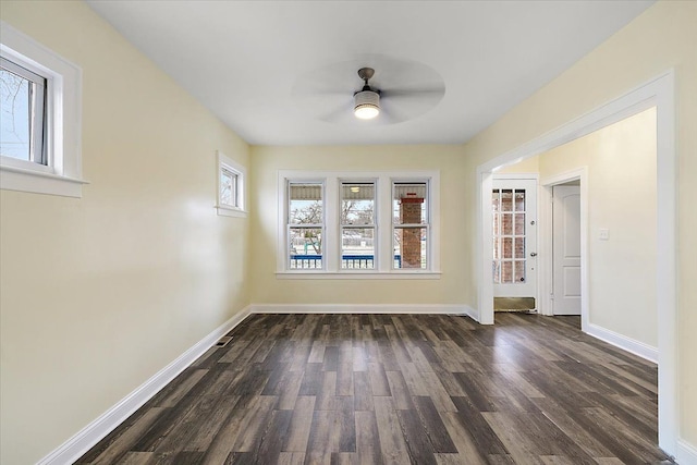 empty room featuring ceiling fan, baseboards, and dark wood-style flooring