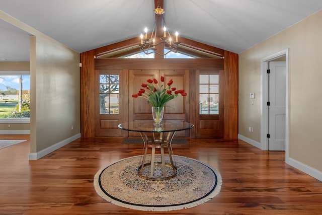 entrance foyer with a chandelier, wood finished floors, lofted ceiling, and baseboards