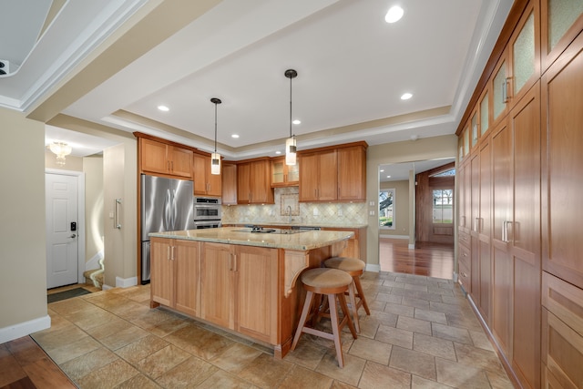 kitchen featuring stainless steel appliances, stone tile floors, baseboards, backsplash, and a raised ceiling