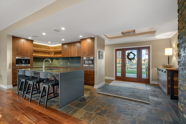 kitchen with stainless steel oven, baseboards, open shelves, and a sink