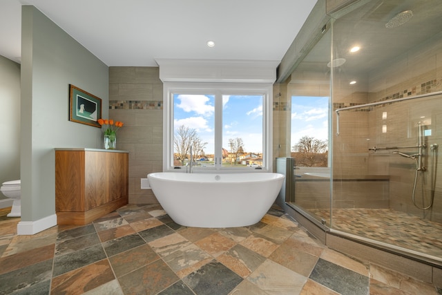 bathroom featuring stone tile floors, recessed lighting, a shower stall, and a freestanding bath