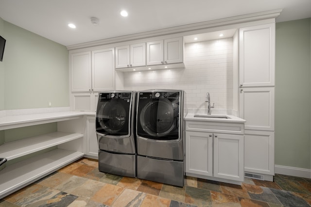clothes washing area with recessed lighting, stone tile floors, a sink, separate washer and dryer, and cabinet space