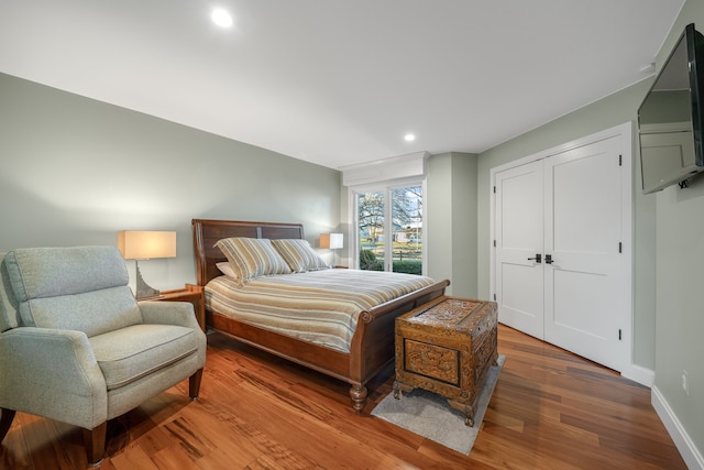 bedroom with recessed lighting, wood finished floors, and baseboards