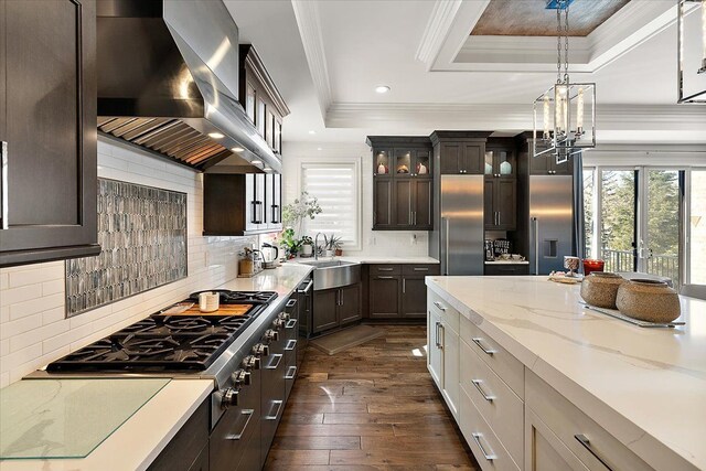 3888 Thatcher Dr, Rochester Hills, MI 48309 - kitchen featuring a raised ceiling, wall chimney range hood, ornamental molding, a sink, and appliances with stainless steel finishes
