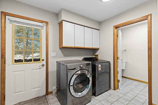laundry room featuring cabinet space, baseboards, light tile patterned floors, and washing machine and clothes dryer