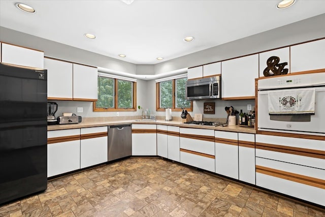 kitchen featuring white cabinets, stainless steel appliances, and stone finish flooring