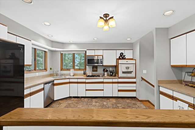 kitchen with a sink, stone finish floor, stainless steel appliances, and white cabinetry