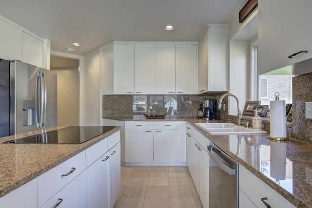 kitchen featuring light stone countertops, appliances with stainless steel finishes, a sink, recessed lighting, and backsplash