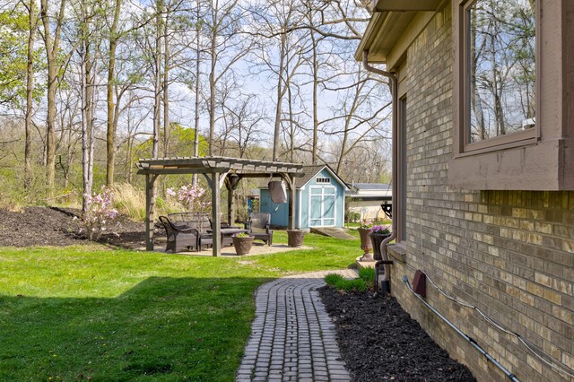 view of yard with an outbuilding, a shed, an outdoor fire pit, a patio, and a pergola