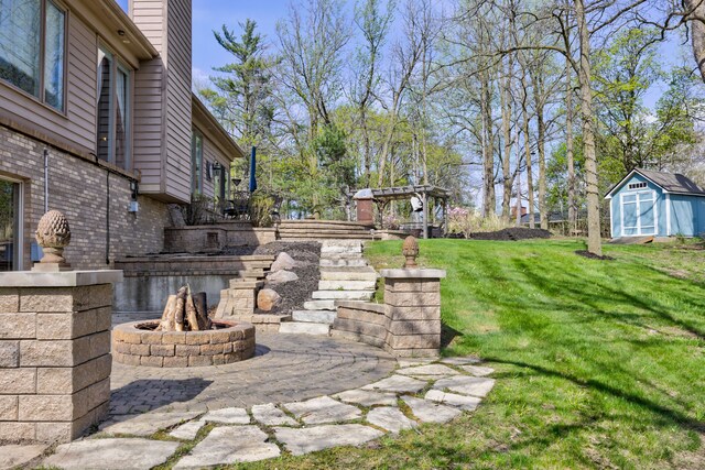 view of yard with an outbuilding, a fire pit, a patio area, and a storage shed