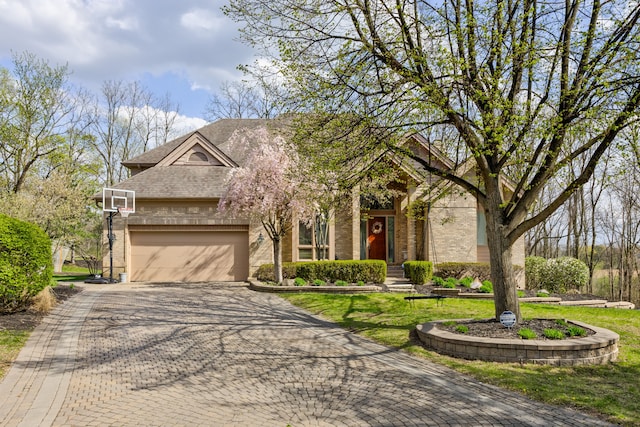 traditional home featuring brick siding, decorative driveway, an attached garage, and a front lawn