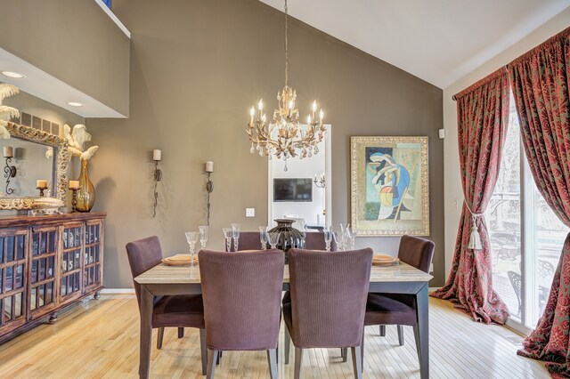 dining space with high vaulted ceiling, a notable chandelier, baseboards, and light wood finished floors