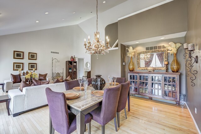 dining room featuring visible vents, light wood finished floors, a chandelier, and high vaulted ceiling
