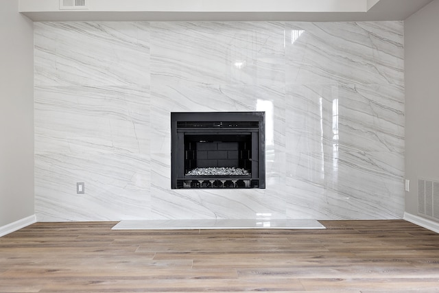 room details featuring a high end fireplace, wood finished floors, visible vents, and baseboards