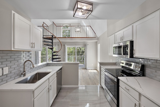 kitchen featuring backsplash, appliances with stainless steel finishes, white cabinetry, and a sink