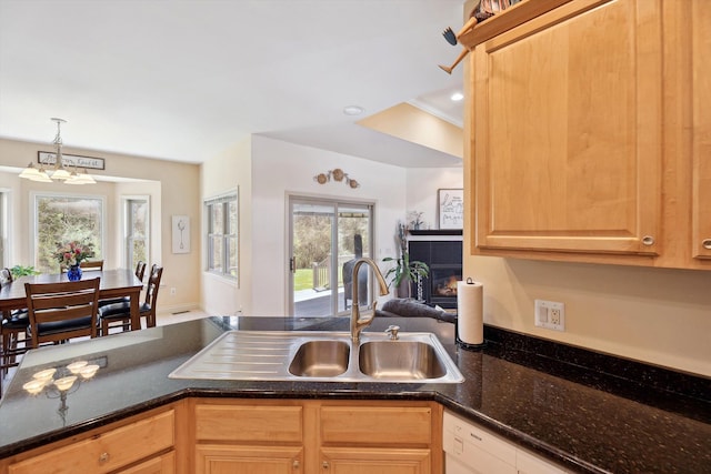 11613 Butler Rd, Willis, MI 48191 - kitchen featuring a sink, dark stone countertops, light brown cabinets, a lit fireplace, and hanging light fixtures