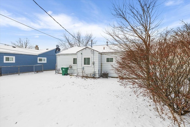 snow covered rear of property featuring fence