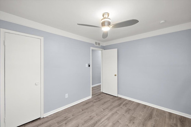 unfurnished bedroom with visible vents, baseboards, a ceiling fan, and wood finished floors