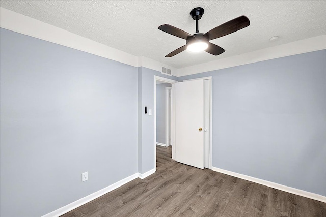 unfurnished room with a ceiling fan, wood finished floors, a textured ceiling, baseboards, and visible vents
