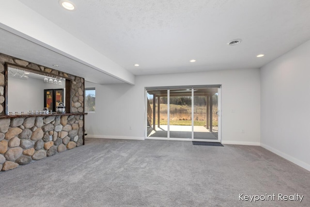 unfurnished living room with a healthy amount of sunlight, carpet flooring, and baseboards