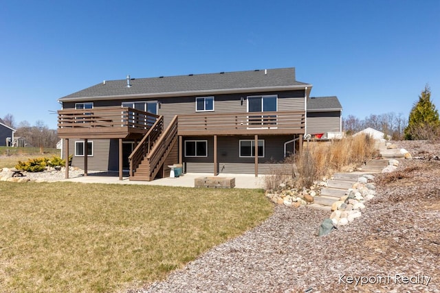 rear view of property featuring a wooden deck, a lawn, stairs, and a patio