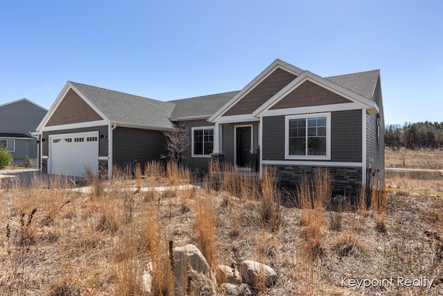 craftsman inspired home with stone siding, an attached garage, a shingled roof, and driveway