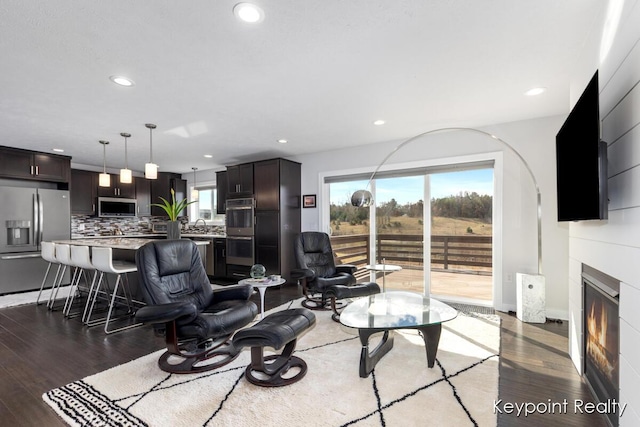 living area featuring a glass covered fireplace, light wood finished floors, and recessed lighting