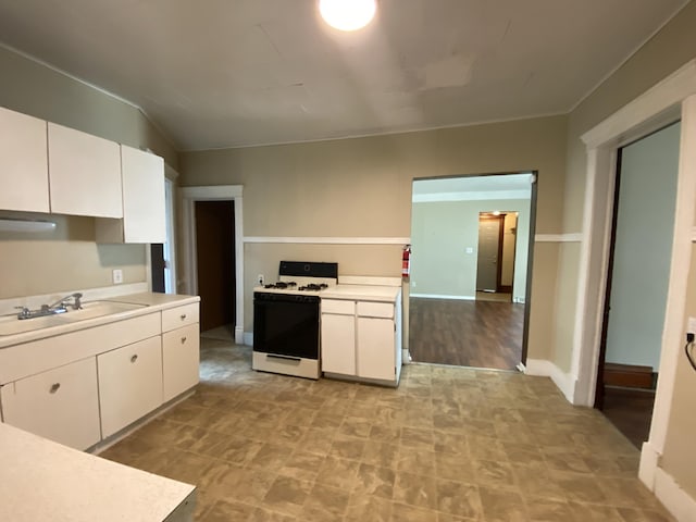 617 Forest St, Kalamazoo, MI 49008 - kitchen featuring white cabinets, a sink, baseboards, white gas stove, and light countertops