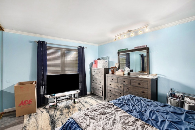 bedroom featuring baseboards, wood finished floors, and crown molding