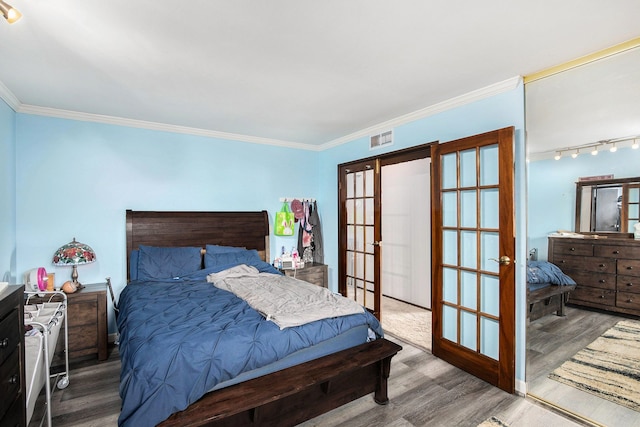 bedroom with ornamental molding, french doors, wood finished floors, and visible vents