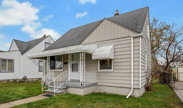 bungalow featuring fence, board and batten siding, a shingled roof, and a front yard