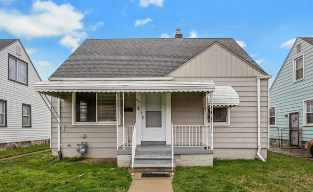 bungalow with a front yard, a shingled roof, board and batten siding, and covered porch