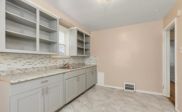 kitchen with a sink, decorative backsplash, open shelves, visible vents, and baseboards