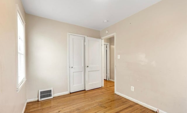 unfurnished bedroom featuring visible vents, light wood-style flooring, multiple windows, and baseboards
