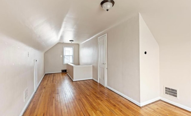 additional living space with vaulted ceiling, visible vents, light wood-style flooring, and baseboards