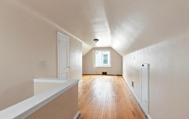 bonus room featuring lofted ceiling, visible vents, light wood-style flooring, and baseboards