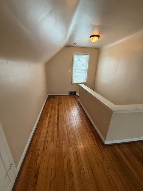 bonus room with visible vents, baseboards, vaulted ceiling, and wood-type flooring