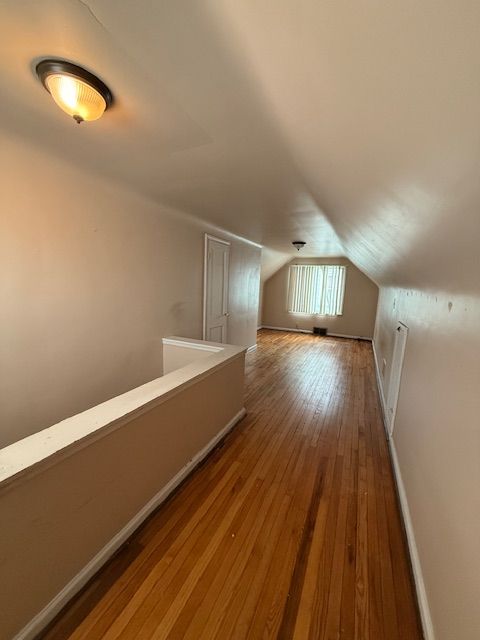 bonus room with lofted ceiling, hardwood / wood-style flooring, and baseboards