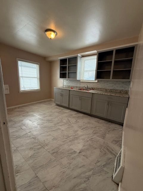 kitchen featuring a sink, plenty of natural light, open shelves, and gray cabinets