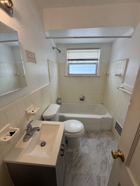 full bath featuring toilet, tile walls, vanity,  shower combination, and marble finish floor