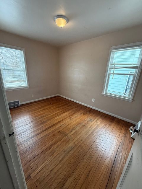 unfurnished room with hardwood / wood-style floors and baseboards