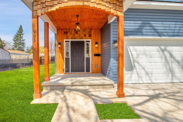 entrance to property featuring fence, a lawn, and an attached garage