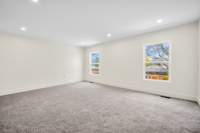 carpeted empty room with baseboards, visible vents, and recessed lighting