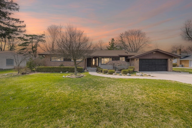 view of front of house with brick siding, a garage, a front lawn, and concrete driveway