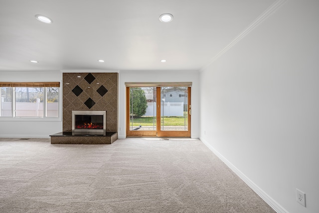 unfurnished living room featuring baseboards, ornamental molding, carpet, and a large fireplace
