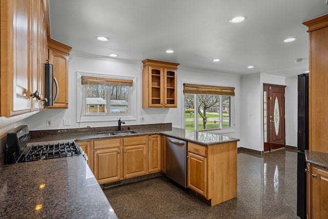 kitchen with a peninsula, appliances with stainless steel finishes, ornamental molding, and a sink