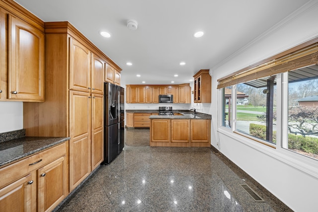kitchen featuring black fridge with ice dispenser, visible vents, baseboards, stove, and stainless steel microwave