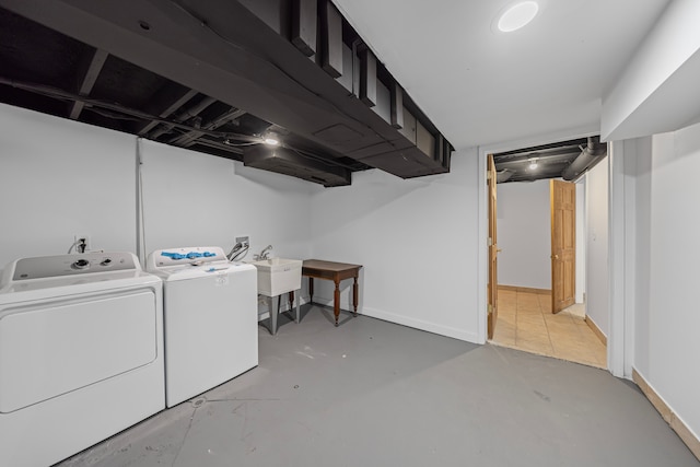 clothes washing area featuring laundry area, a sink, baseboards, and washing machine and clothes dryer