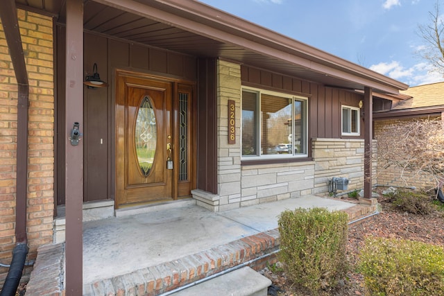 doorway to property featuring board and batten siding and stone siding